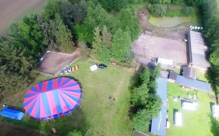Das Bild zeigt eine Luftaufnahme vom Gelände der Rancho Acapulco. 
				Das Zirkuszelt für die Nacht der Gaukler ist bereits aufgebaut. Außerdem sieht man die Ställe und Wiesen der Pferde-Ranch.